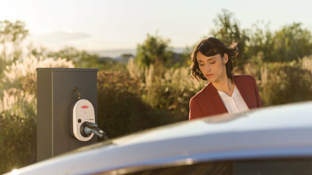 Fronius Wattpilot EV Charger with a woman standing beside a car