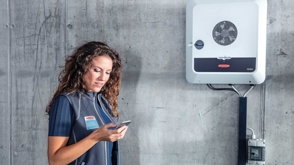 Person checking phone near Fronius GEN24 inverter.
